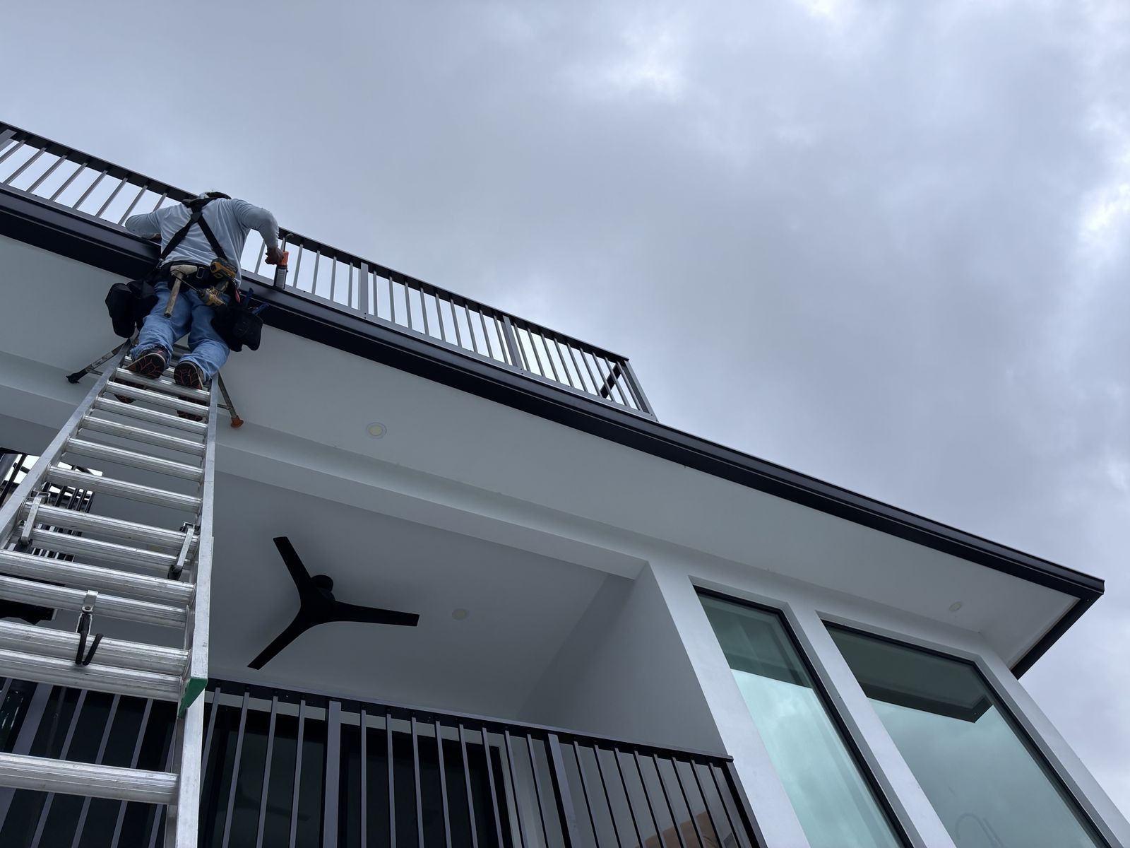 Installing seamless gutter from a ladder with a safety harness