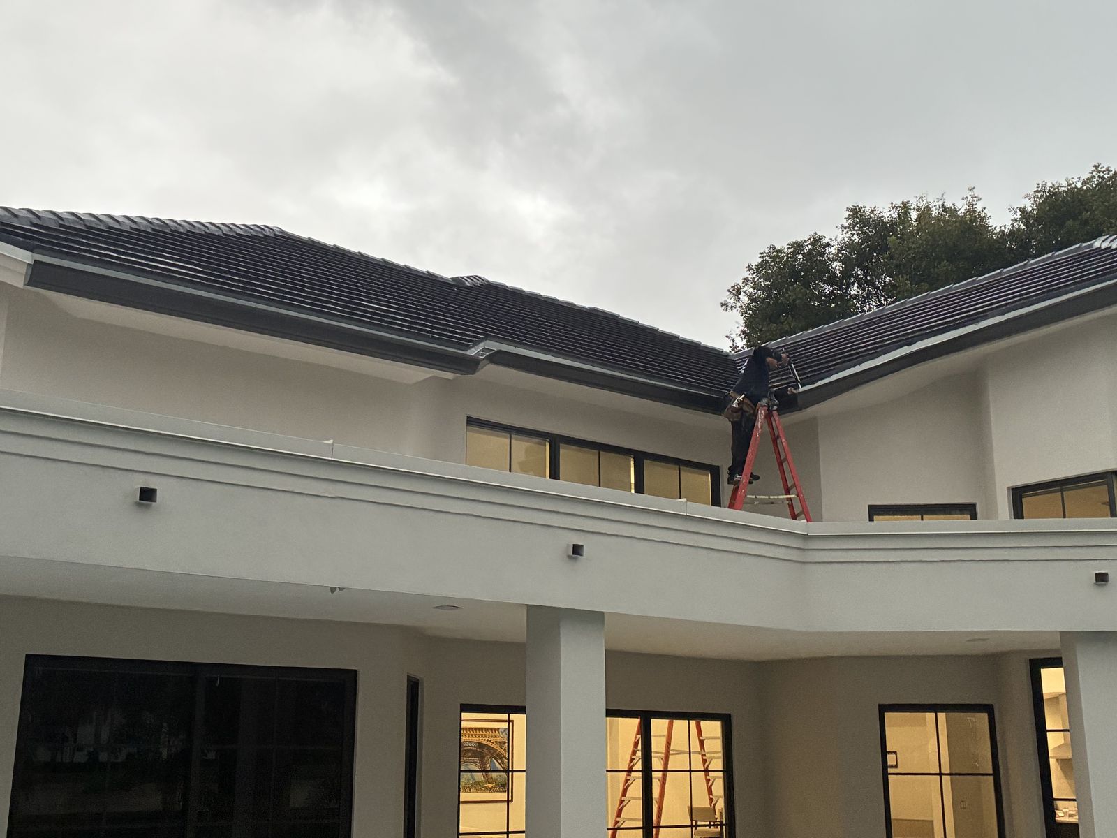 Installing seamless gutter from a ladder on a two-story home