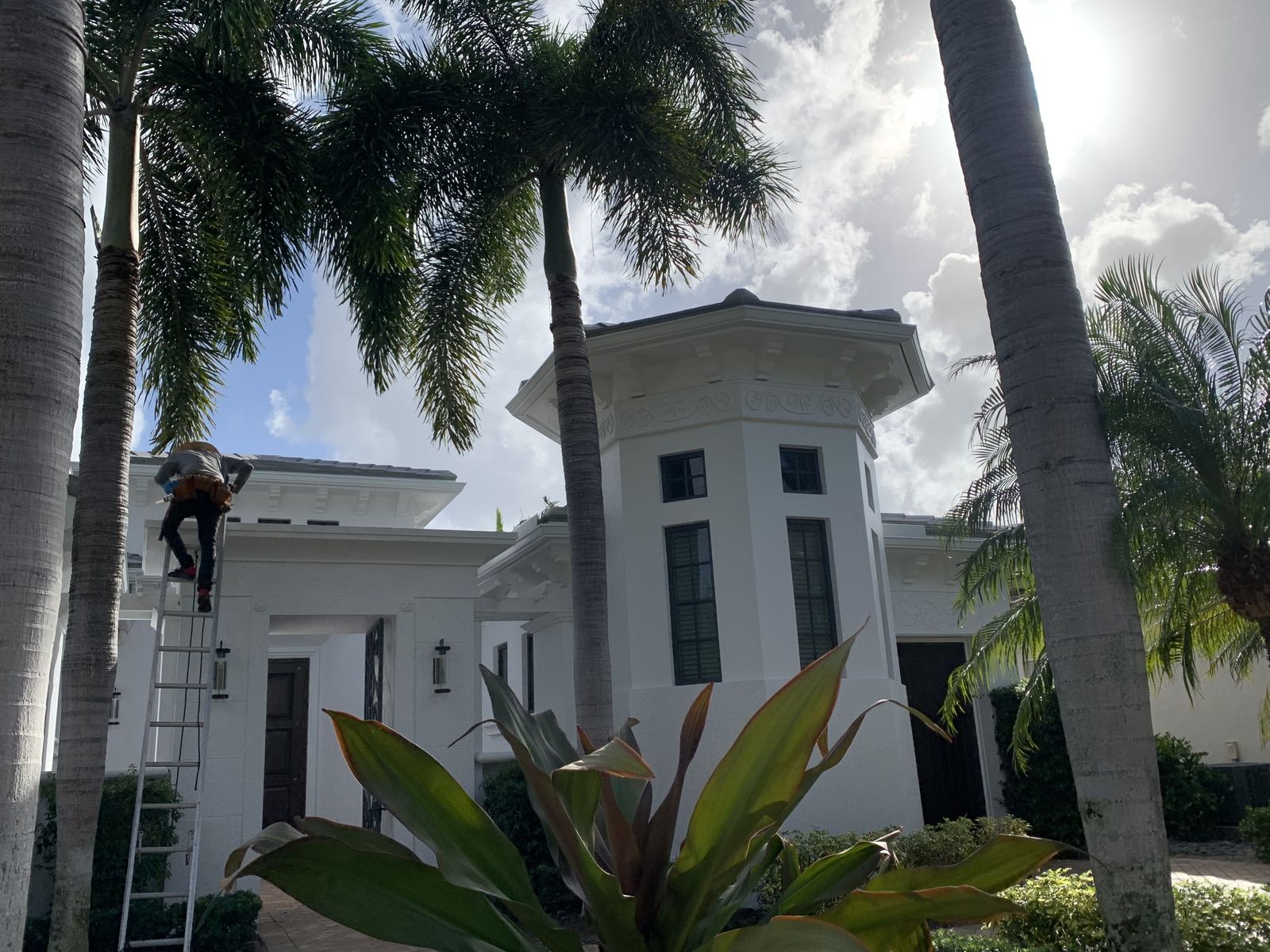 Technician on a ladder working along the roofline of a South Florida home