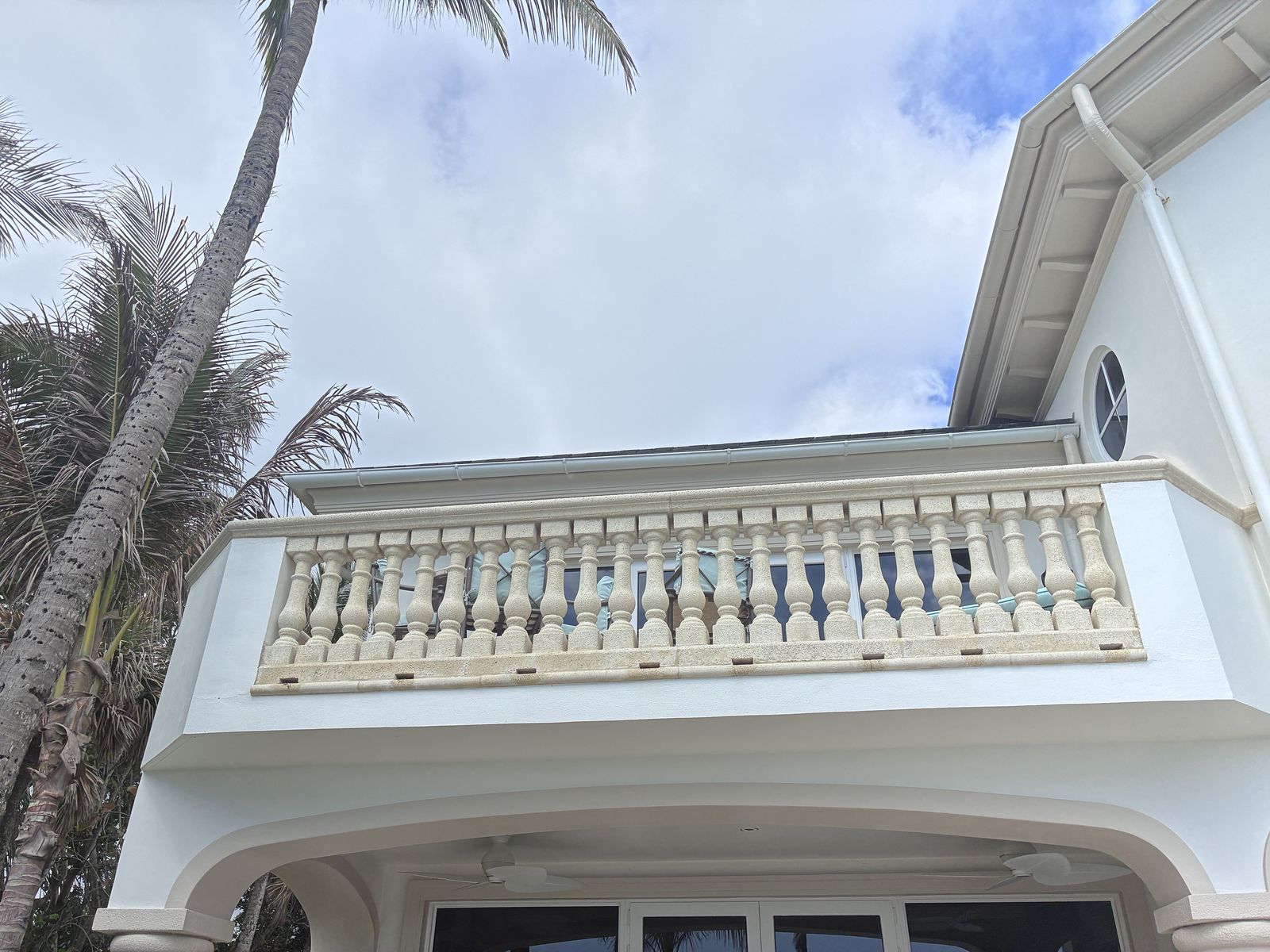 White seamless gutters and downspout on a two-story home with balcony