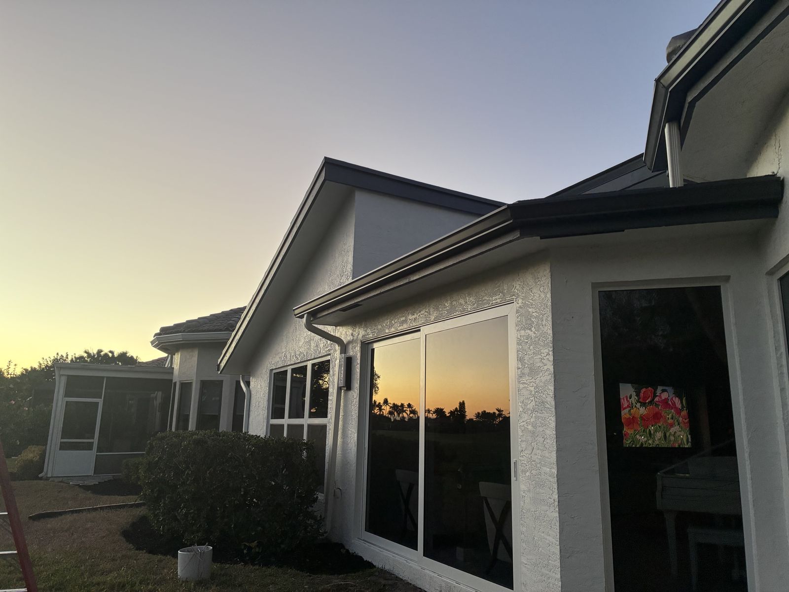 Seamless gutters at dusk on a South Florida home with a screened lanai