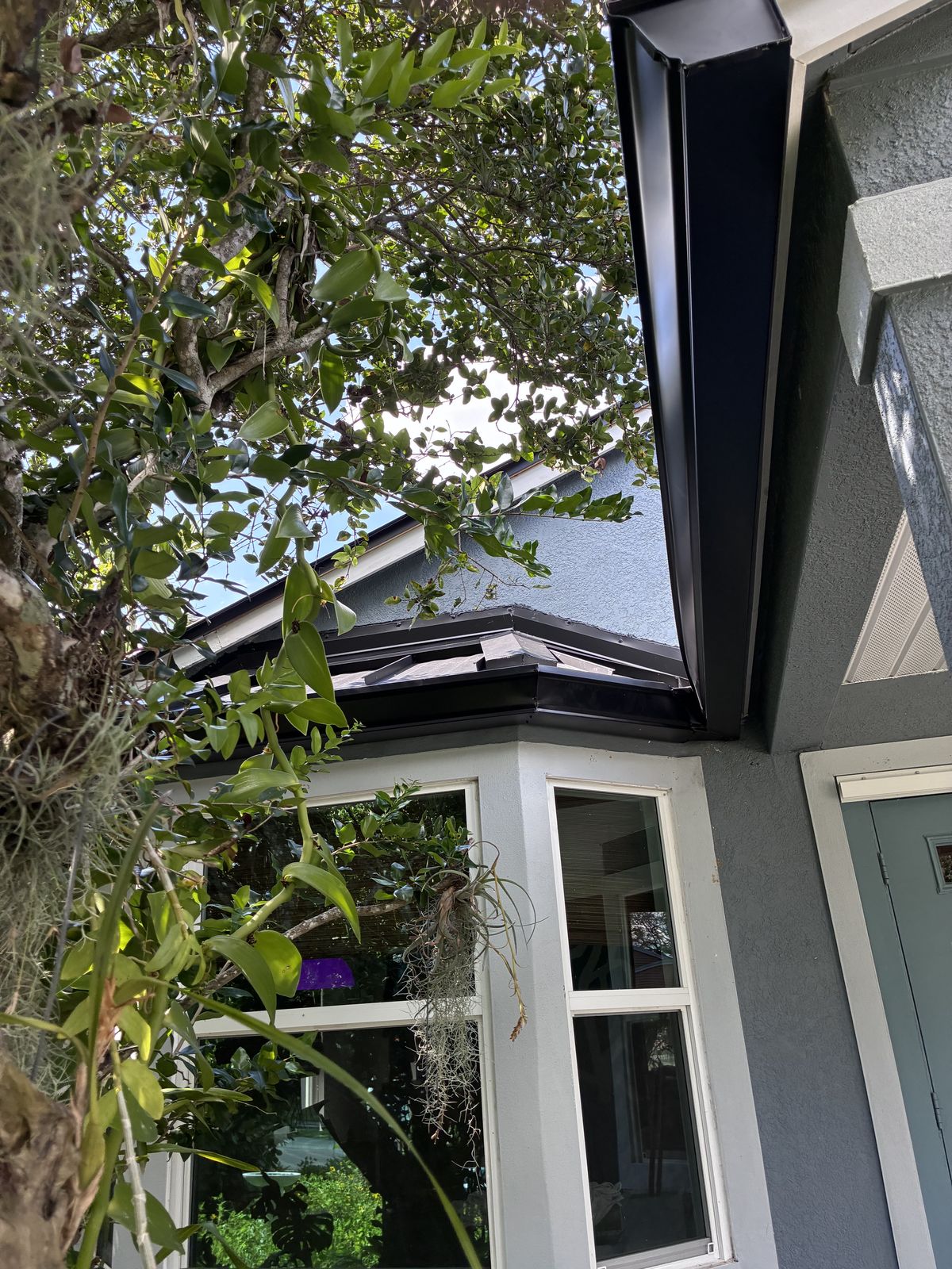 Black seamless gutter and downspout on a home corner