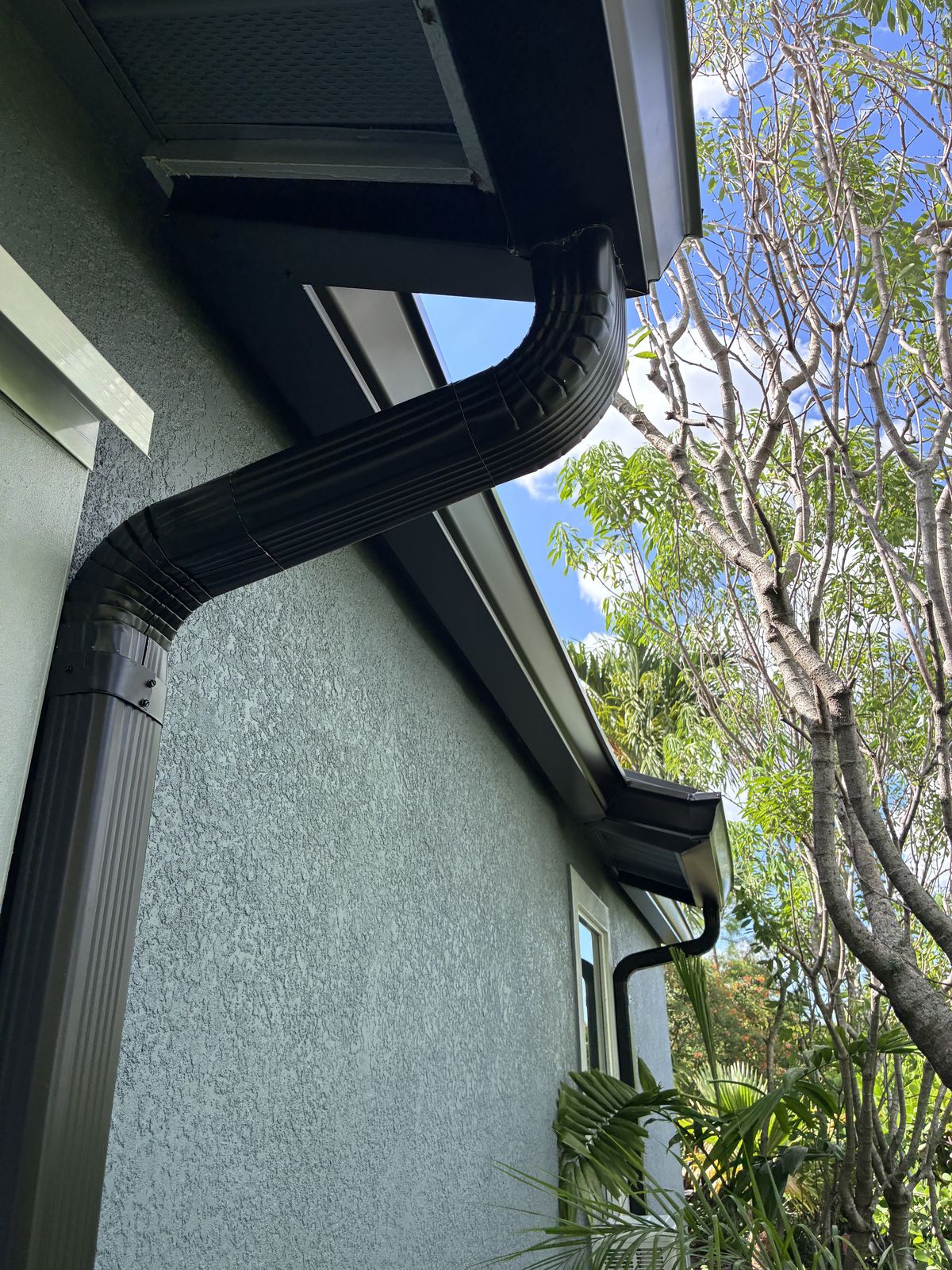 Close-up of a black seamless gutter and downspout