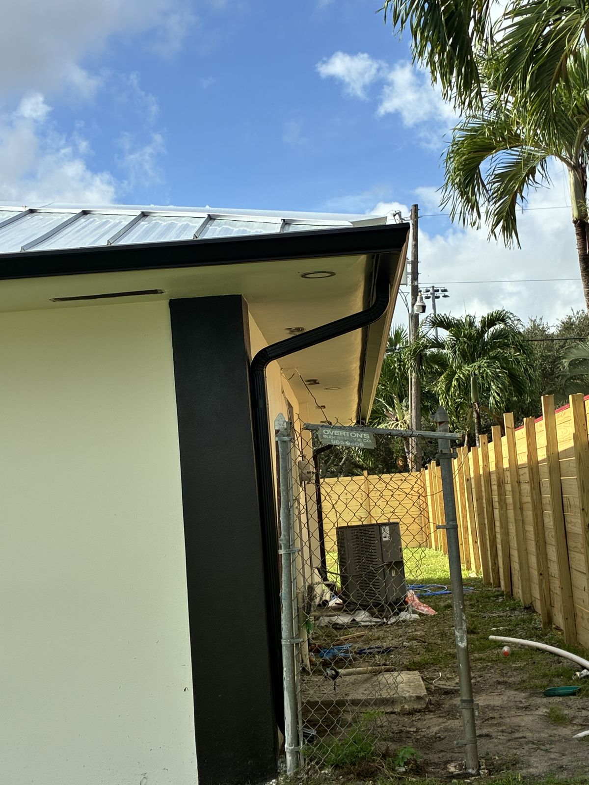 Black seamless gutter and downspout on a modern metal-roof home