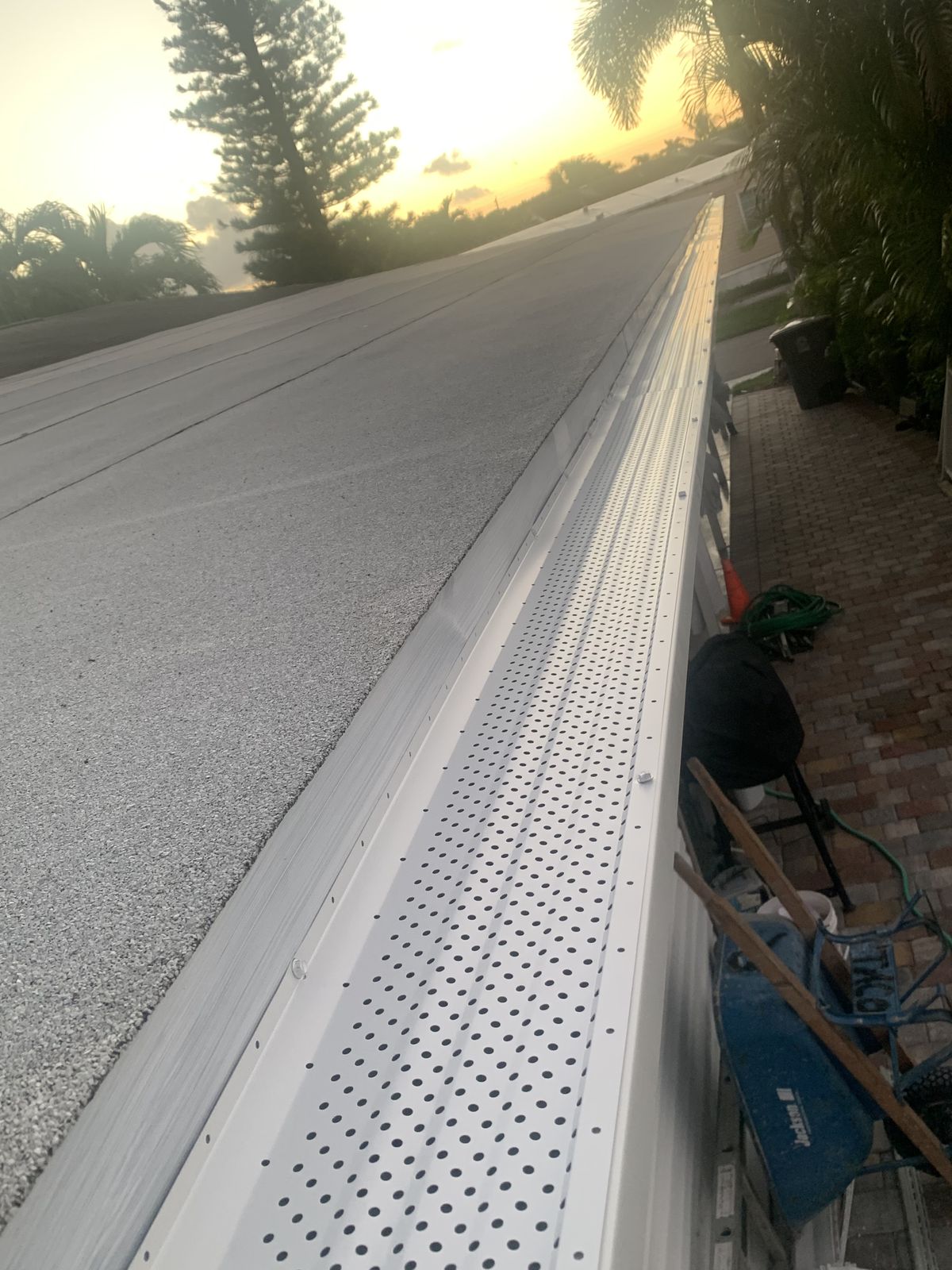 Perforated aluminum gutter guard / leaf guard fitted along a gutter at dusk
